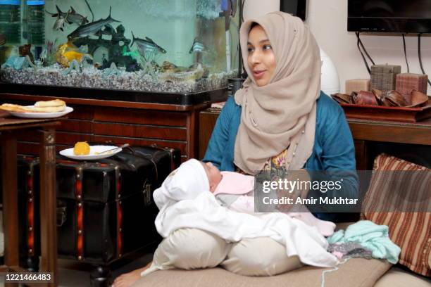 mother in veil (hijab) with her 3 months old daughter in her lap. - punjab pakistan stock pictures, royalty-free photos & images