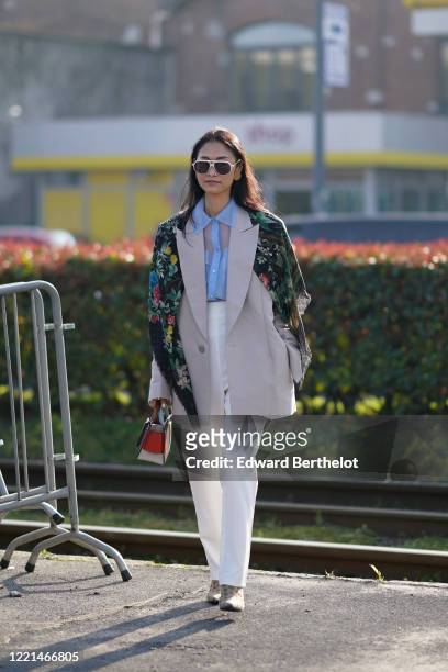 Fashion blogger Pornwika wears sunglasses, earrings, a Gucci floral print scarf over the shoulders, a blue mesh shirt, a gray oversized blazer...