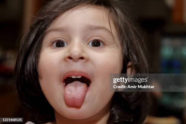 a little girl with mouth open and sticking her tongue out. - tongue stock pictures, royalty-free photos & images