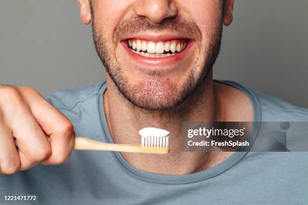 dental hygiene: cropped image of a smiling man about to brush his teeth - teeth cleaning stock pictures, royalty-free photos & images