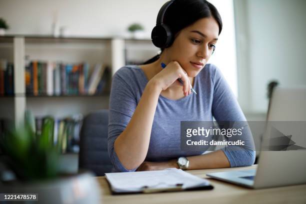jonge vrouw met hoofdtelefoons die van huis werken - internet stockfoto's en -beelden