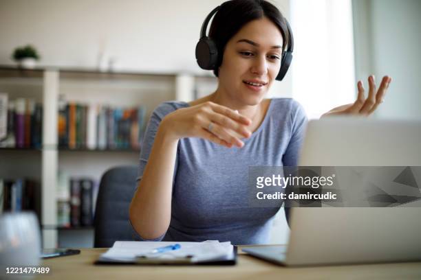 giovane donna che ha una videochiamata sul computer portatile a casa - spiegare foto e immagini stock