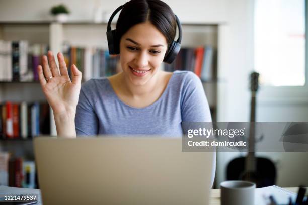 young smiling woman having video call on laptop computer at home - mentoring virtual stock pictures, royalty-free photos & images