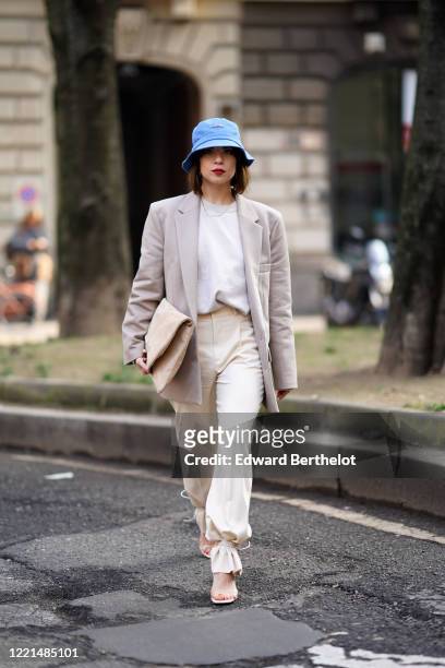 Francesca Cina wears a blue bob hat, a gray oversized blazer jacket, a white t-shirt, white pants, a bag, shoes, outside Calcaterra, during Milan...