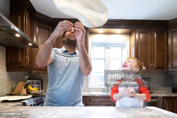 padre e piccolo figlio rossa che fanno la pizza fatta in casa - pizza toss foto e immagini stock