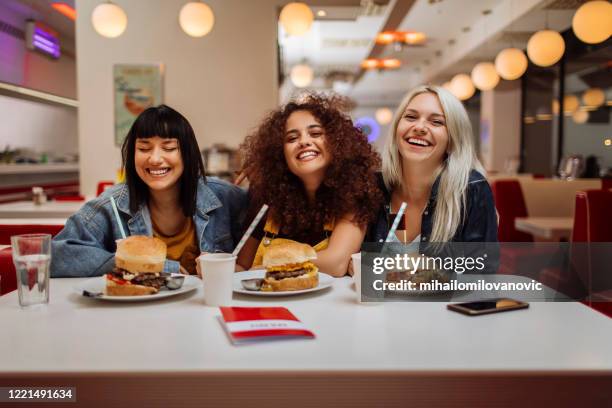 sie gehen dorthin, wo die burger gut sind - girls laughing eating sandwich stock-fotos und bilder