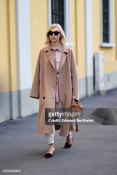 Guest wears sunglasses, a beige long wool coat, a brown leather bag, sandals, outside Tod's, during Milan Fashion Week Fall/Winter 2020-2021 on...