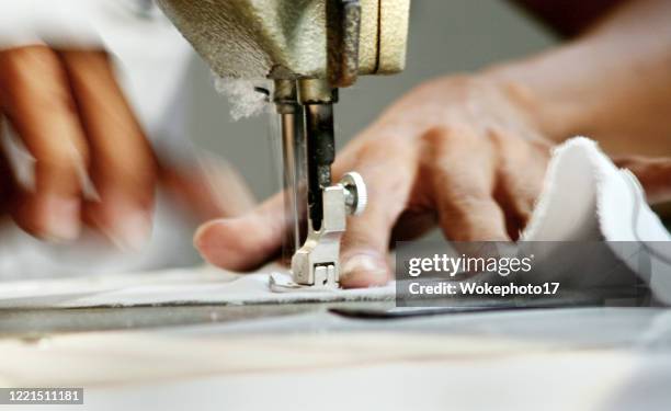 close-up of man worker sewing clothing in garment factory - fashion close up stock-fotos und bilder