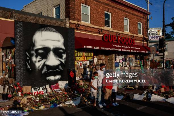 Kids pose as their father takes a photo in front of a makeshift memorial to George Floyd near the site where he died in police custody, in...