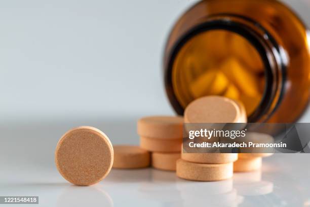 yellow vitamin pills isolated on a white background - vitamina c foto e immagini stock