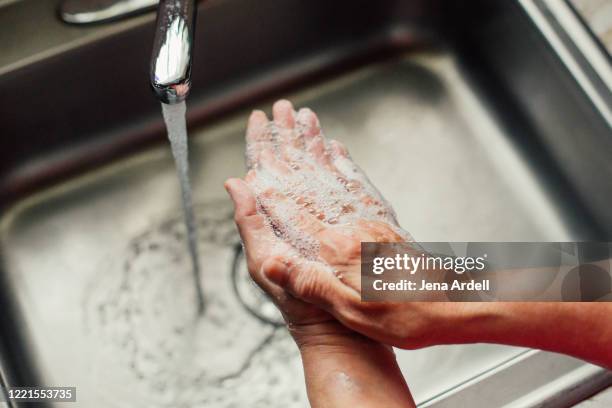 closeup woman washing hands in kitchen sink - zwangsstörung stock-fotos und bilder