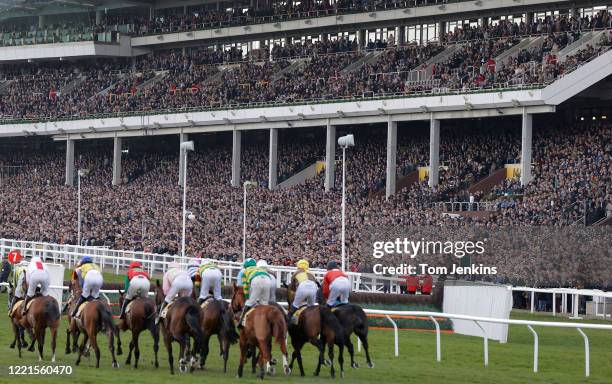 Runners in the first race pass the packed stands during day four of the Cheltenham National Hunt Racing Festival at Cheltenham Racecourse on March...