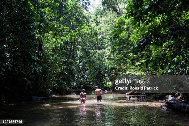 Man and a woman walk in a river in the jungle on October 1, 2012 in Utria National Park, Colombia. The Utria National Park lies in the Pacific...