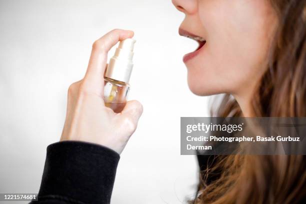 a woman using a fresh breath mouth spray - bad breath stock pictures, royalty-free photos & images