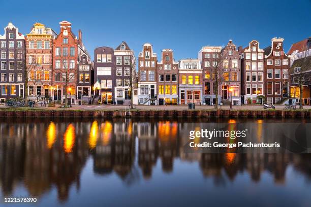 row of houses in the canals of amsterdam - amsterdam stock-fotos und bilder