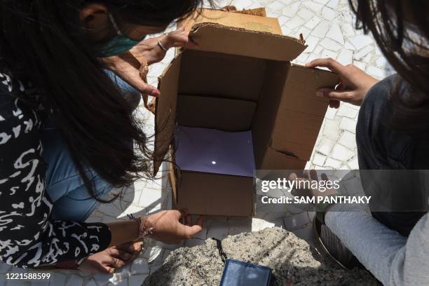 Staff members of The Gujarat Council on Science & Technology observe an annular solar eclipse through a pinhole box at a GUJCOST facility in...