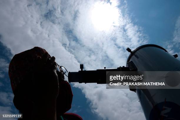Man observes the annular solar eclipse with a telescope in Kathmandu on June 21, 2020.