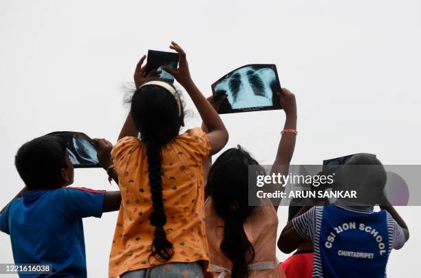 Children witness an annular solar eclipse with a X-Ray film in Chennai on June 21, 2020.