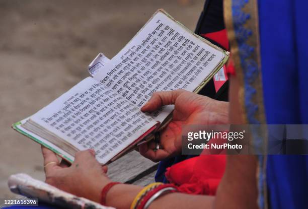Woman reads a religious book on the banks of sangam, confluence of Ganges , Yamuna and mythical Saraswati river , during the annual 'Ring of Fire'...