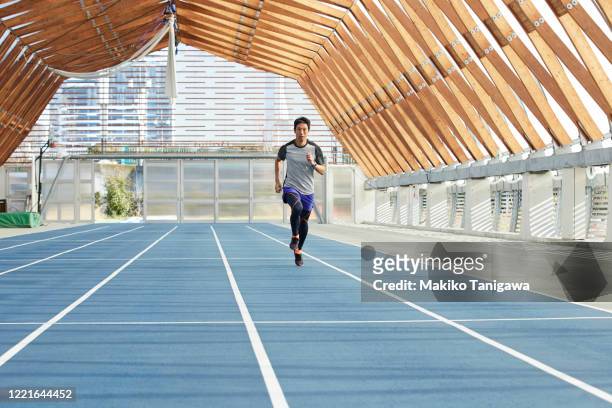 mature japanese sportsman running on track - tartanbahn stock-fotos und bilder