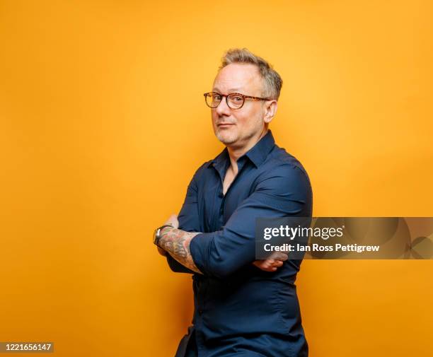 middle-aged businessman with blue shirt on yellow background - gelber hintergrund stock-fotos und bilder
