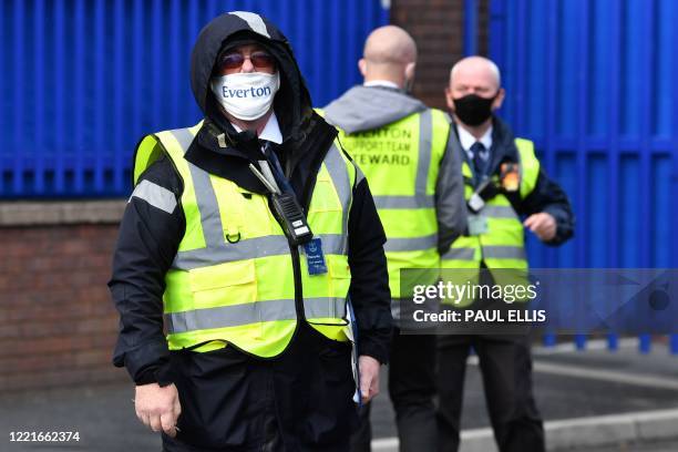 An Everton steward wears a protective face mask as he patrols outside the ground ahead of the English Premier League football match between Everton...