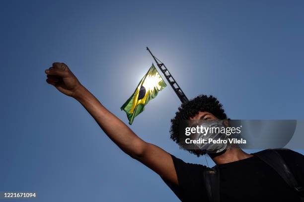 Protester wearing a face mask shouts slogans during an anti-racist protest condemning the government of President Jair Bolsonaro amidst the...