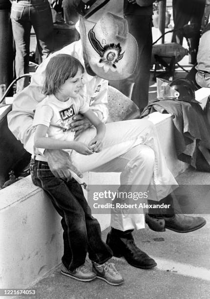 Driver Richard Petty sits with his granddaughter along pit road prior to the start of the 1986 Firecracker 400 stock car race at Daytona...