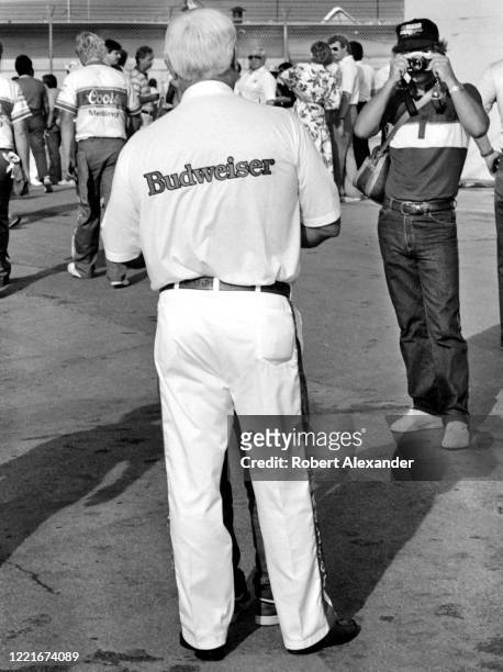 Fan takes a photograph of race car owner Junior Johnson in the speedway garage area prior to the start of the 1986 Firecracker 400 stock car race at...