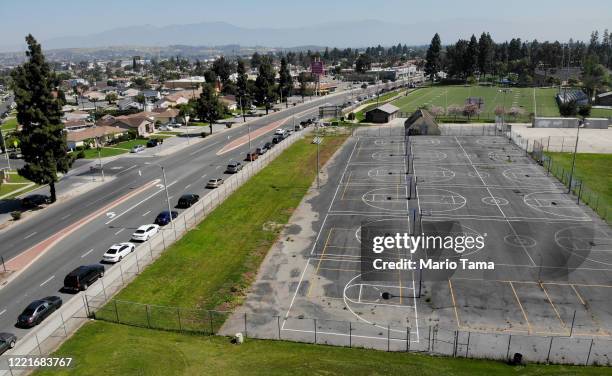 An aerial view of cars lined up to receive food distributed by the Los Angeles Regional Food Bank and the city, as basketball courts and a football...