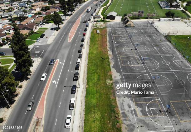 An aerial view of cars lined up to receive food distributed by the Los Angeles Regional Food Bank and the city, as basketball courts and a football...