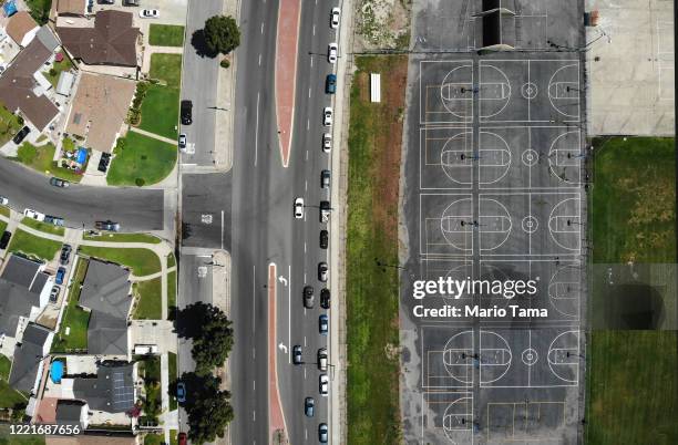 An aerial view of cars lined up to receive food distributed by the Los Angeles Regional Food Bank and the city, as basketball courts stand empty at...