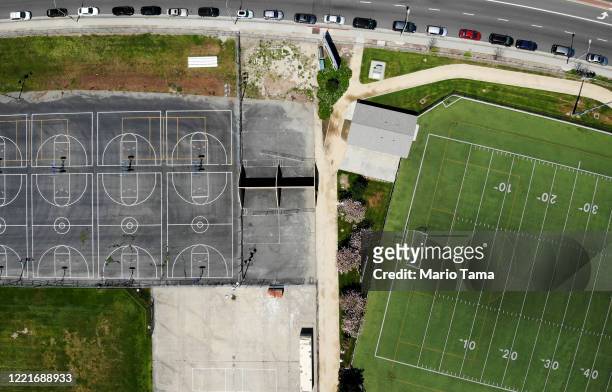 An aerial view of cars lined up to receive food distributed by the Los Angeles Regional Food Bank and the city, as basketball courts and a football...