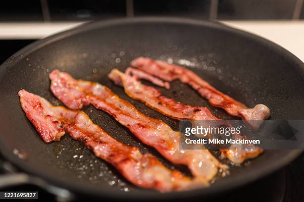 bacon cooking in a frypan - bacon fotografías e imágenes de stock