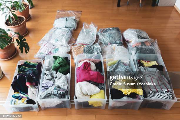 woman organizes clothes in living room of her home - declutter stock pictures, royalty-free photos & images