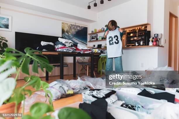 woman organizes clothes in living room of her home - commode stockfoto's en -beelden