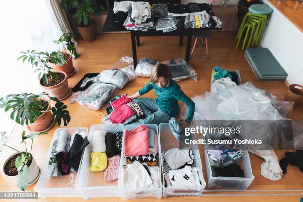 woman organizes clothes in living room of her home - arrangement photos et images de collection