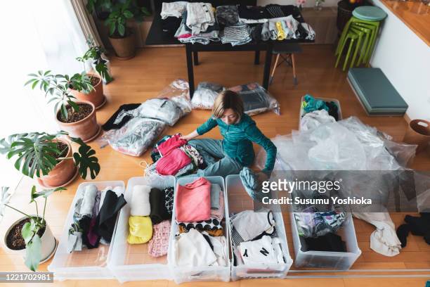 woman organizes clothes in living room of her home - arrangiare foto e immagini stock