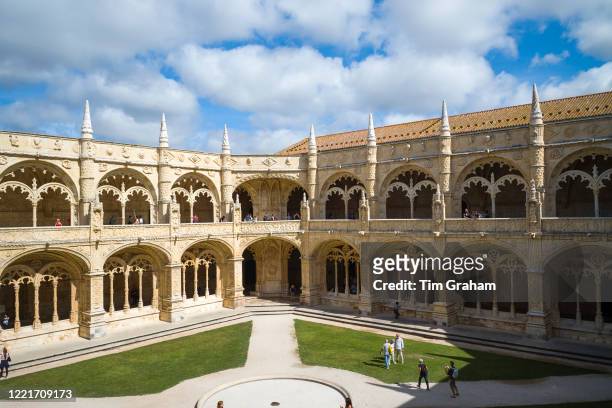 Tourists pass stone pillars and cloisters of famous Monastery of Jeronimos - Mosteiro dos Jeronimos in Lisbon, Portugal.