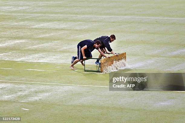 Employees try to slide the water from the pitch with banks as the the European Field Hockey championships in Monchengladbach were hit by heavy rain...