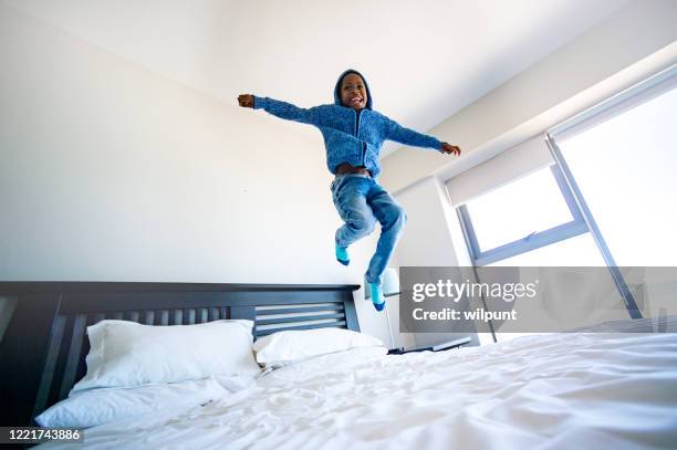 cola de encierro trampolín saltando - a boy jumping on a bed fotografías e imágenes de stock