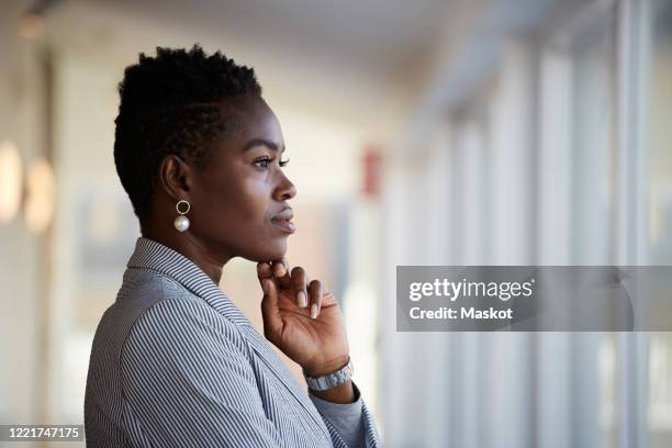 side view of confident female entrepreneur looking away while standing at workplace - business woman side stockfoto's en -beelden