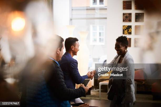 smiling businessman shaking hands with female entrepreneur in office seminar - representative member of congress stockfoto's en -beelden