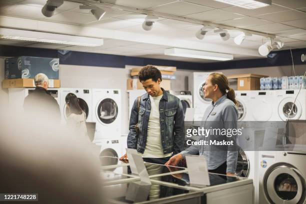 mature owner talking to male customer in electronics store - appliance shopping stock pictures, royalty-free photos & images