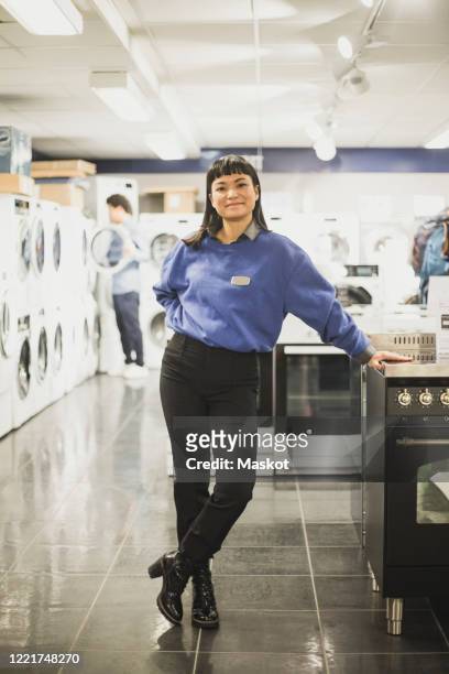 portrait of smiling saleswoman standing in electronics store - assistant bildbanksfoton och bilder