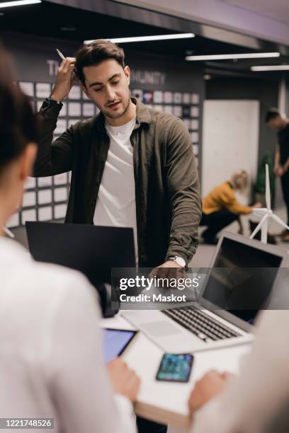 businessman writing in diary while brainstorming with colleagues at office desk - permanent representative stock pictures, royalty-free photos & images