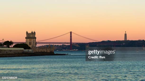 belem tower and bridge of april 25 at sunset (lisbon, portugal) - belem stock-fotos und bilder