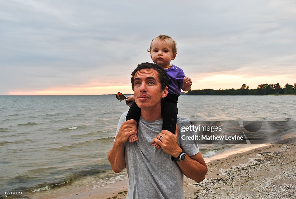 Father carrying daughter on shoulders on beach