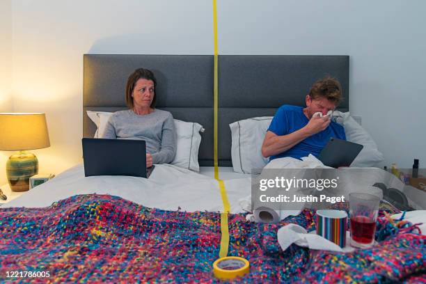 couple in bed with territory marked by tape - abstand halten infektionsvermeidung stock-fotos und bilder
