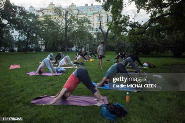 People practice yoga on June 22, 2020 at Riegrovy sady park in Prague, Czech Republic.